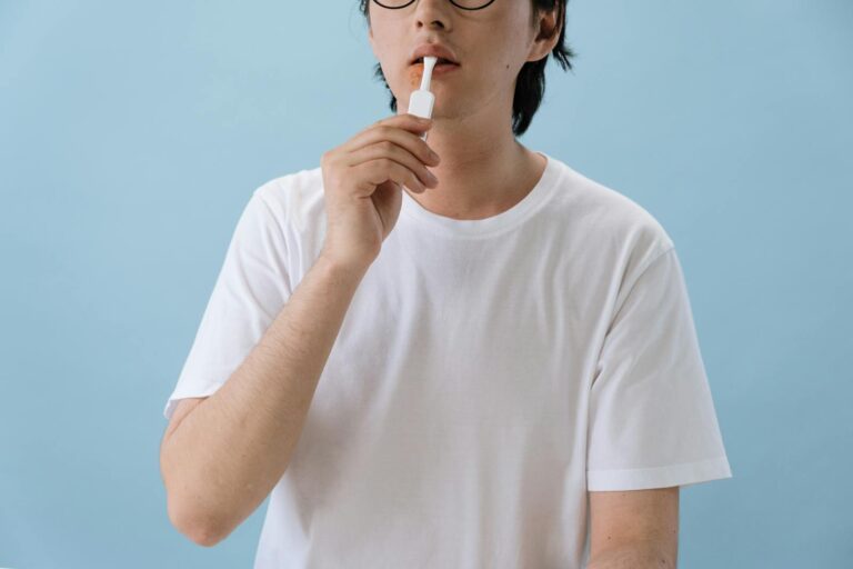 Herpes in 24 Stunden weg – Ist das wirklich möglich? A person in white T-shirt using an oral swab test kit indoors with a blue background.