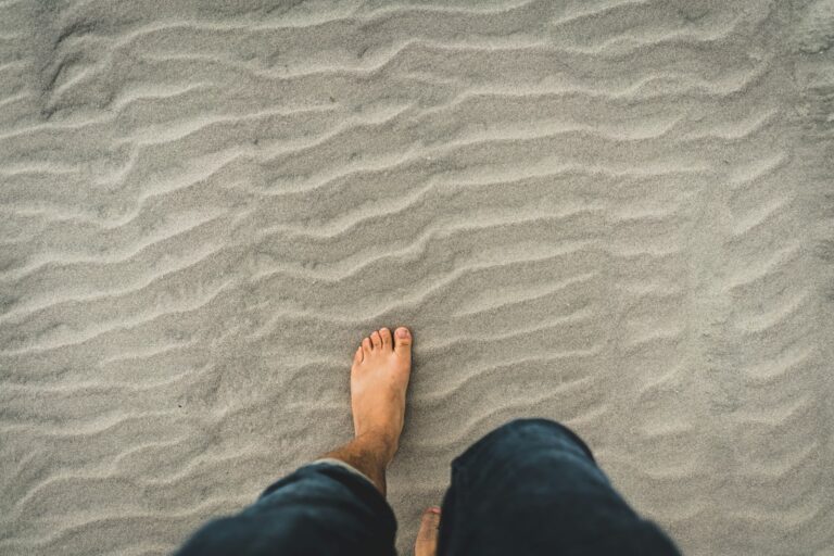 Stechender Schmerz an der Fußoberseite: Mögliche Ursachen und was jetzt hilft man in blue denim jeans walking through the sand